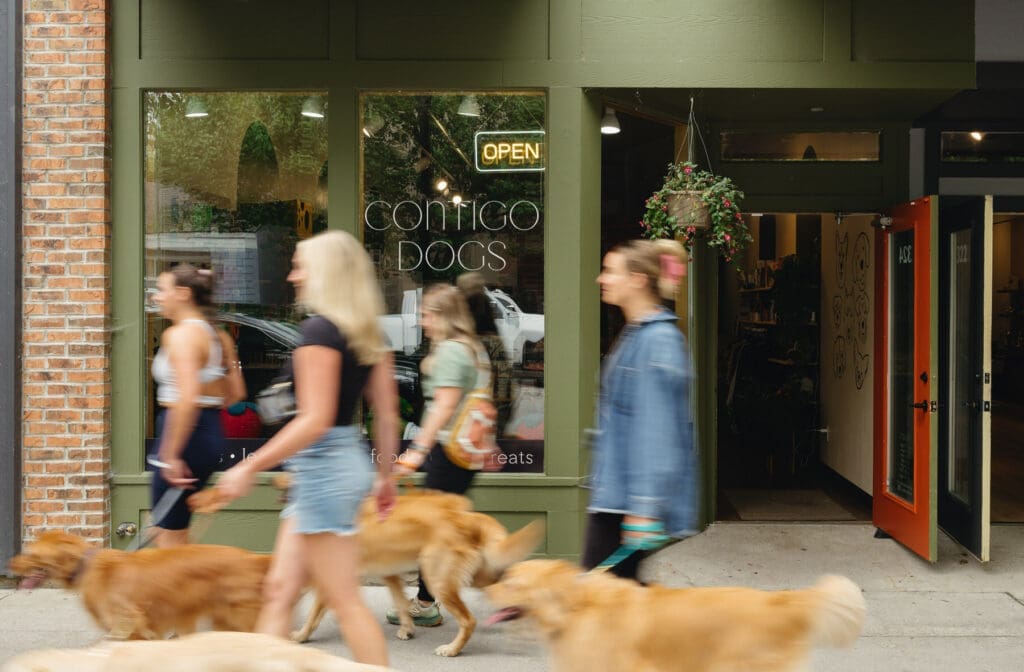 women walking their golden retrievers in front of the Contigo Dogs storefront in Traverse City Michigan