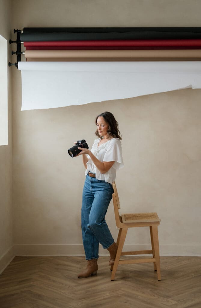 woman photographer looking at the back of her camera during her branding photo session at Somewhere Haus in Grand Rapids, Michigan