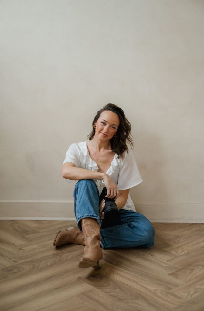 woman sitting on the floor inside Somewhere Haus photo studio in Grand Rapids holding her Sony camera 